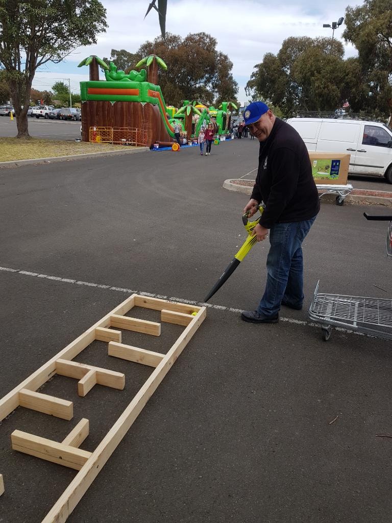 Knight setting up a cornhole game at an outdoor community event